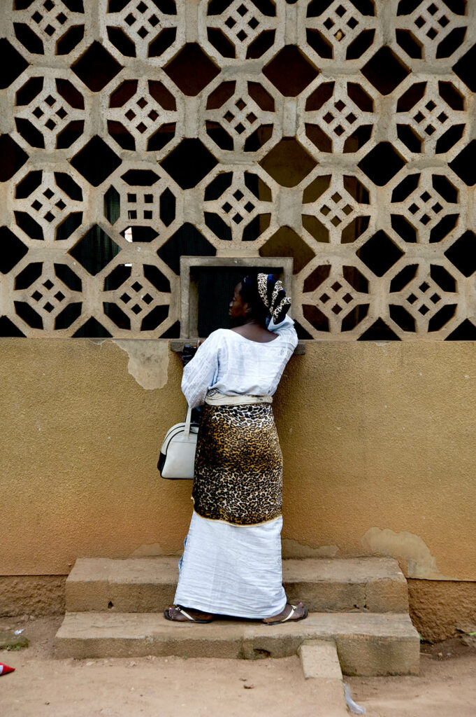 Une femme se tient de dos à l’entrée d’un dispensaire médical. Abomey. Bénin. François Guibilato photographe.