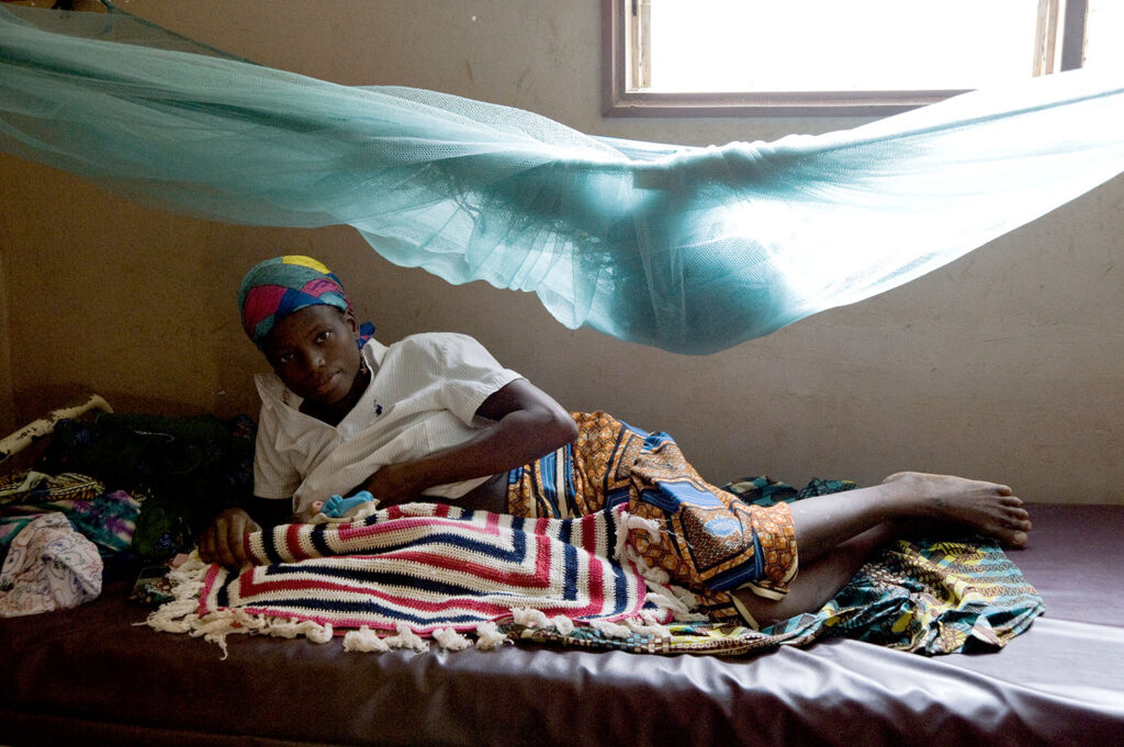 Une femme dans un lit d’hôpital allaite son enfant. Scène d'intérieur. Street photographie. Couleurs. François Guibilato photographe.