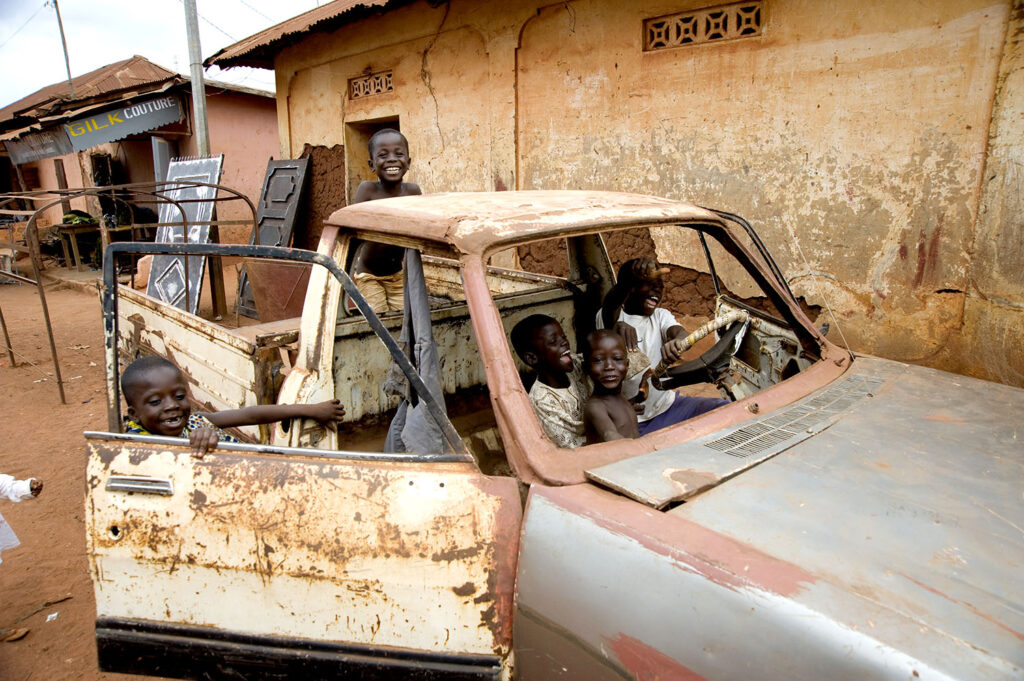 Des enfants jouent dans une voiture abandonnée. Scène de rue. Street photographie. Couleurs. François Guibilato photographe.