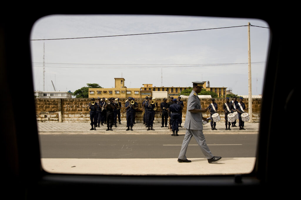 Un militaire marche dans la rue. Il est accompagné par des musiciens. Abomey. Bénin. François Guibilato photographe.