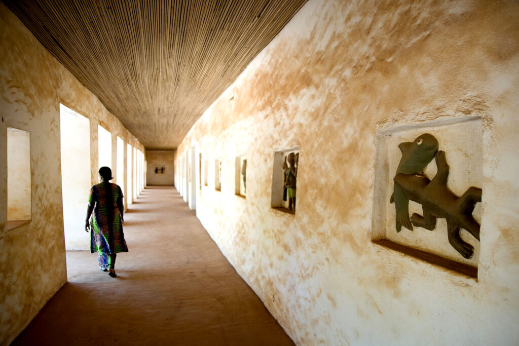 Une femme marche dans les couloirs des Palais royaux d’Abomey. Bénin. François Guibilato photographe.