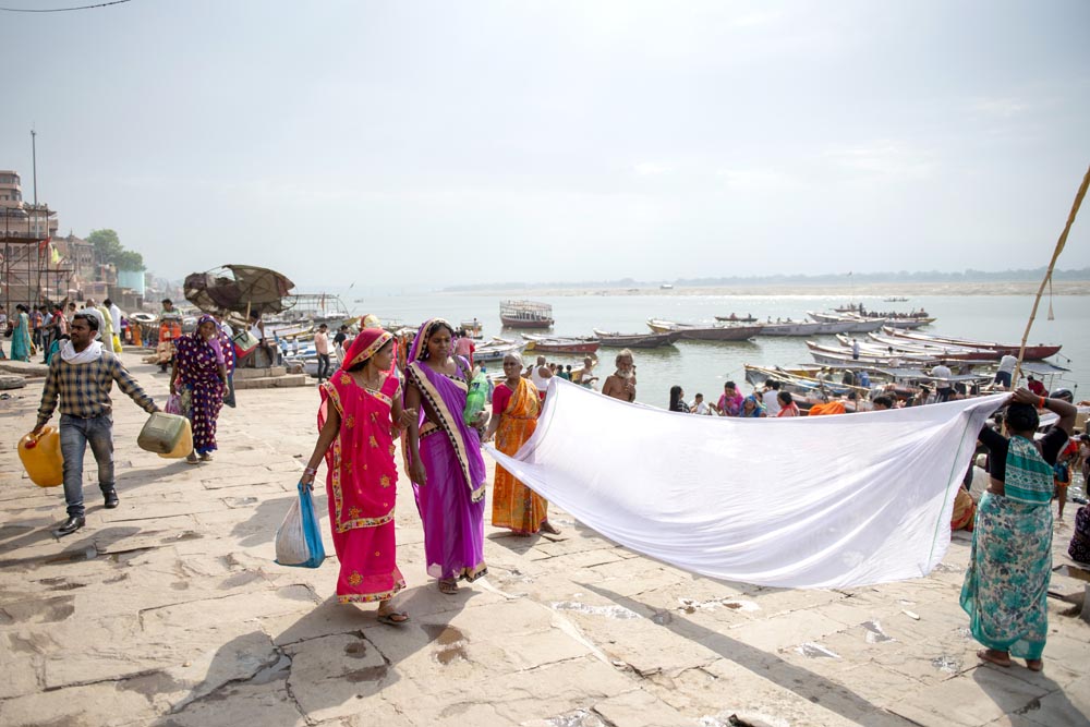 Street photographie. Des femmes font sécher un drap au soleil. Ghats de Varanasi. Couleurs. Varanasi. Bénarès. François Guibilato Photographe.