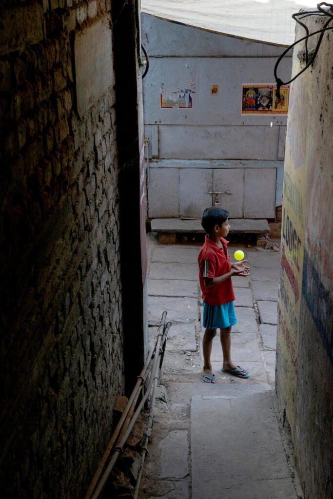 Un enfant joue avec une balle dans la rue. Street photographie. Couleurs. Varanasi. François Guibilato Photographe.