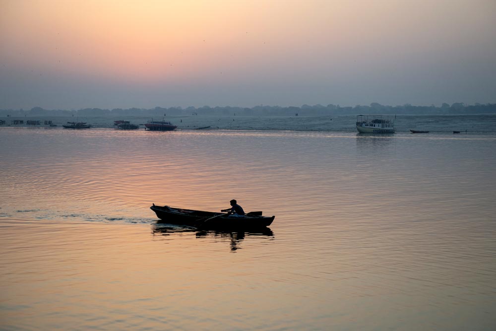 Une barque glisse le long de la rivière Gange. Coucher de soleil. Couleurs. Bénarès. Varanasi. François Guibilato Photographe.