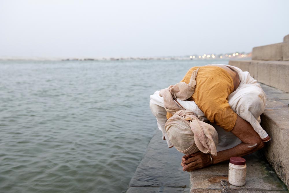 Scène de rue. Street photographie. Une femme prie. Ghats de Bénarès. Couleurs. Varanasi. François Guibilato Photographe.