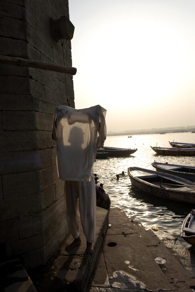 Un homme fait sécher son linge. Ghats de Varanasi. Contre jour. Lever de soleil. Couleurs. Varanasi. François Guibilato Photographe.